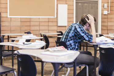 Genervter Teenager mit Kopf in den Händen im Klassenzimmer der High School - ISF07870