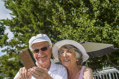 Glückliches älteres Paar, das ein Mobiltelefon benutzt - ISF07879