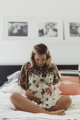 Schwangere Frau auf dem Bett, die den Bauch berührt - ISF07883
