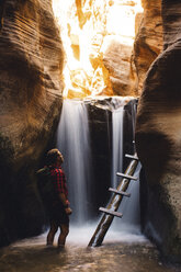 Wanderer in Sandsteinhöhle bei Wasserfall, Kanarraville, Utah, USA - ISF07890