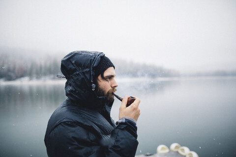 Seitenansicht eines Pfeife rauchenden Mannes am See, Bass Lake, Kalifornien, USA, lizenzfreies Stockfoto