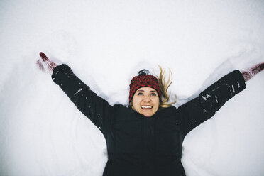 Woman lying on back in snow arms open - ISF07902