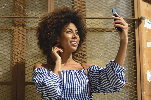 Lächelnde junge Frau nimmt Selfie mit Handy, lizenzfreies Stockfoto