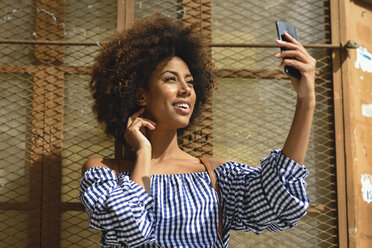 Smiling young woman taking selfie with cell phone - JSMF00255