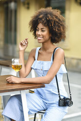 Porträt einer modischen jungen Frau mit Kamera beim Biertrinken im Freien - JSMF00268