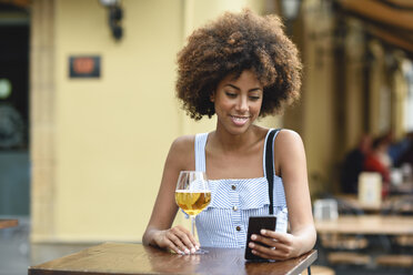 Porträt einer jungen Frau mit Smartphone, die im Freien Bier trinkt - JSMF00271