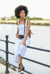 Portrait of fashionable young woman with camera and backpack - JSMF00274