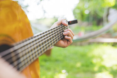 Männerhände spielen akustische Gitarre im Garten - CUF21338