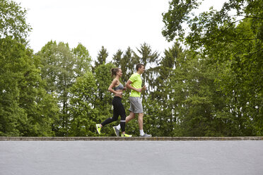 Young man and woman training, running on top of wall - CUF21498