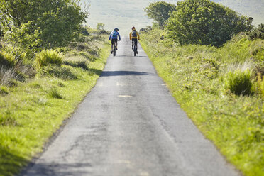 Rear view of cyclists cycling on rural road - CUF21537