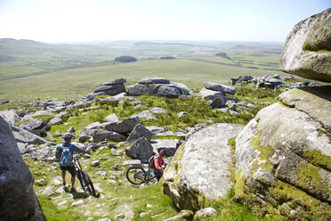 Cyclists carrying bicycles on rocky outcrop - CUF21575