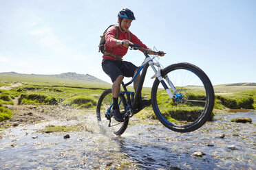 Cyclist doing wheelie through water - CUF21592