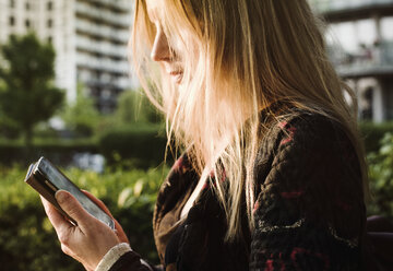 Junge Frau im Freien, die ein Smartphone benutzt - CUF21610