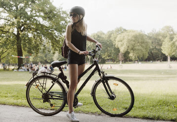 Young woman in park, preparing to ride bicycle - CUF21613