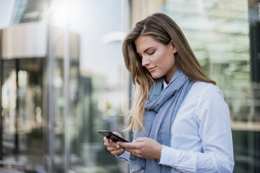 Junge Geschäftsfrau schaut auf ihr Smartphone - DIGF04556