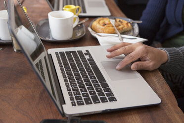 Nahaufnahme eines Paares, das an einem Kaffeetisch sitzt und Laptops benutzt - CUF21622