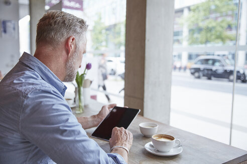 Älterer Mann sitzt in einem Café und benutzt ein digitales Tablet, Rückansicht - CUF21662