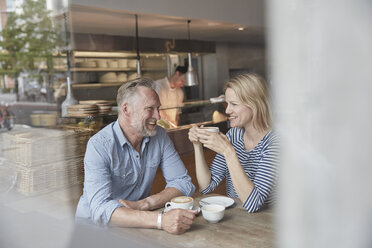 View through window of mature couple in coffee shop chatting - CUF21672
