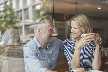 Blick durch das Fenster eines reifen Paares in einem Café von Angesicht zu Angesicht lächelnd - CUF21673