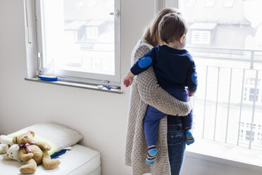 Rear view of mid adult woman and baby son looking through window - CUF21695