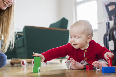 Baby-Mädchen spielt mit Bauklötzen auf dem Boden im Wohnzimmer - CUF21709