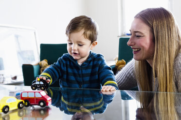 Mid erwachsene Frau und Baby Sohn spielen mit Spielzeugautos auf dem Tisch - CUF21729