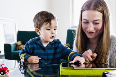 Mittlere erwachsene Frau und kleiner Sohn verwenden Touchscreen auf digitalem Tablet am Tisch - CUF21730