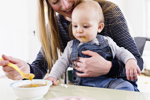 Frau füttert ihre kleine Tochter am Tisch - CUF21741