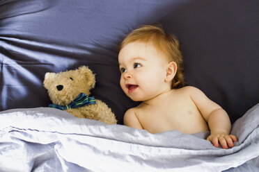 Baby girl lying in bed with teddy bear - CUF21753