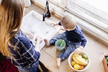 Overhead view of woman at kitchen sink with baby son - CUF21764