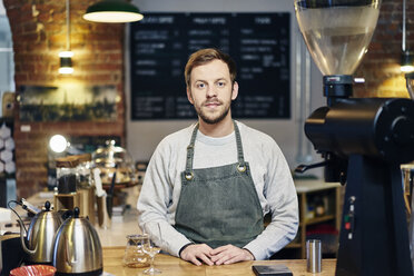 Portrait of young male barista at coffee shop kitchen counter - CUF21796