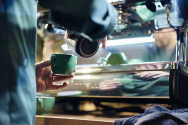 Abgeschnittene Aufnahme eines männlichen Barista, der Milch in eine Tasse in einem Coffeeshop gießt - CUF21800