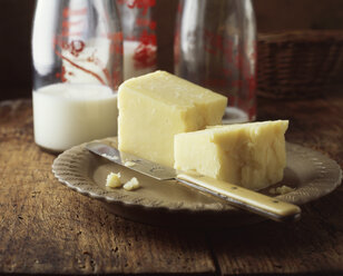 Lebensmittel, Molkerei, reifer Cheddar-Käse, Milchflaschen, traditionelles Bauernhaus - CUF21883