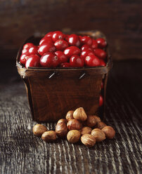 Essen, rustikales Körbchen mit Preiselbeeren und Haselnüssen, Holztisch - CUF21884