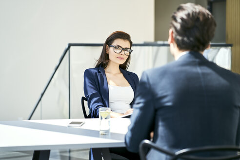 Businesswoman and businessman talking at desk in modern office - BSZF00462