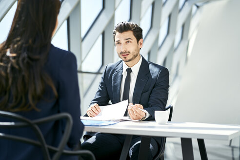 Businessman looking at businesswoman in modern office - BSZF00467