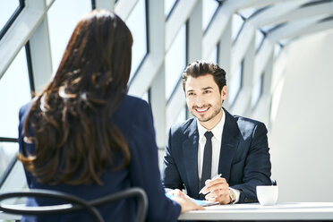 Smiling businessman looking at businesswoman in modern office - BSZF00468