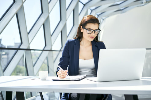 Geschäftsfrau arbeitet am Schreibtisch in einem modernen Büro - BSZF00471