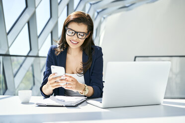 Smiling businesswoman working at desk in modern office - BSZF00476