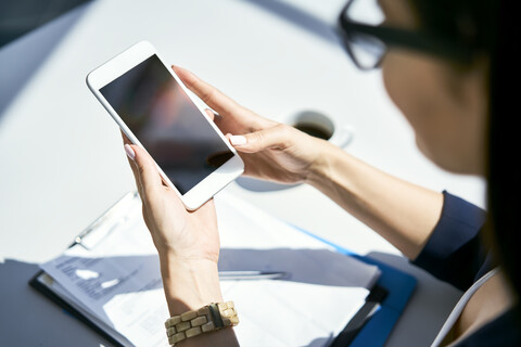 Close-up of businesswoman using cell phone at desk in office stock photo