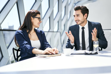 Geschäftsfrau und Geschäftsmann im Gespräch am Schreibtisch in einem modernen Büro - BSZF00488