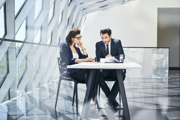 Businesswoman and businessman checking documents at desk in modern office - BSZF00489