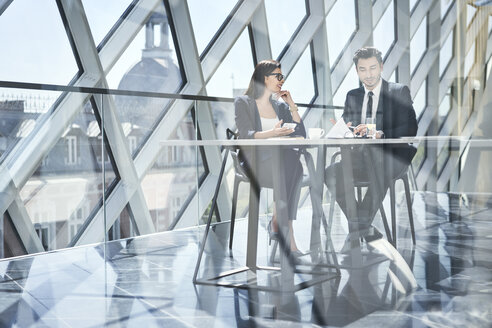 Geschäftsfrau und Geschäftsmann im Gespräch am Schreibtisch in einem modernen Büro - BSZF00490
