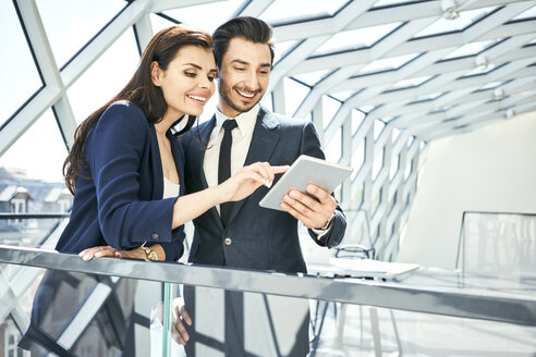 Businesswoman and businessman sharing tablet in modern office - BSZF00519