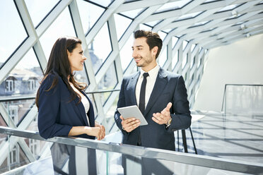 Businesswoman and businessman with tablet talking in modern office - BSZF00520