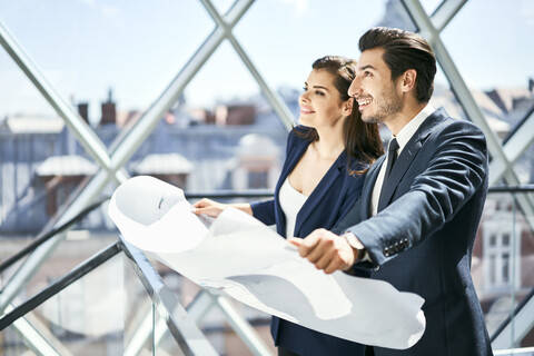 Lächelnde Geschäftsfrau und Geschäftsmann mit Plan im Büro, lizenzfreies Stockfoto