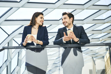 Lächelnde Geschäftsfrau und Geschäftsmann in einer Kaffeepause in einem modernen Büro - BSZF00526