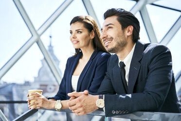 Lächelnde Geschäftsfrau und Geschäftsmann in einer Kaffeepause in einem modernen Büro - BSZF00531