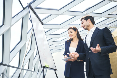 Businessman and businesswoman working with flip chart in office stock photo