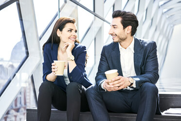 Lächelnde Geschäftsfrau und Geschäftsmann in einer Kaffeepause in einem modernen Büro - BSZF00549